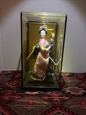 A vintage Japanese geisha doll in a glass display case. picture