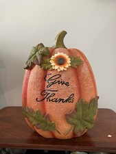 decorative orange resin autumn pumpkin featuring a green stem, a sunflower accen picture