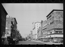 Downtown street scene 1930s cars trolley storefronts municipal building picture