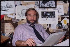 Photo:Tony Auth cartoonist 1980s working in front of sketches of cartoons picture