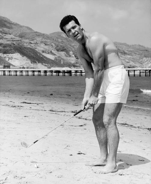 American film star James Garner practises golf stroke beach Malibu- Old Photo