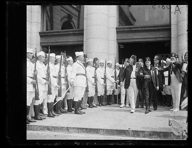 Photo:Shriners 1923 June Uniformed Men with Rifles Parade Outside Building