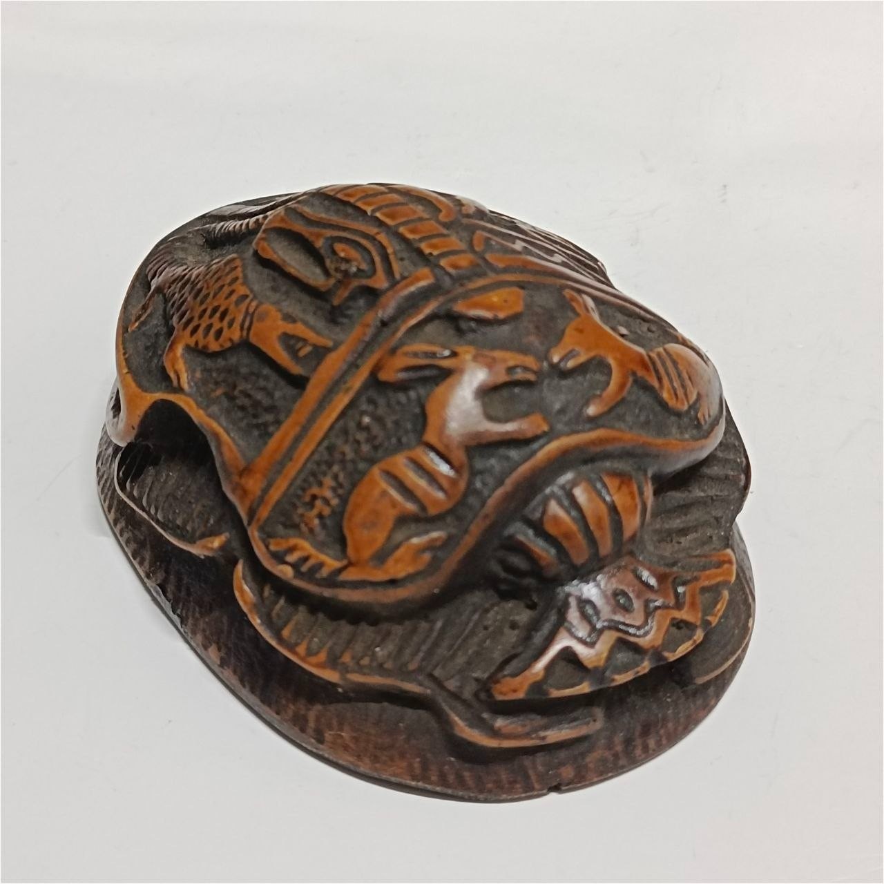Ancient Egyptian scarab carving with intricate patterns brown and orange tones