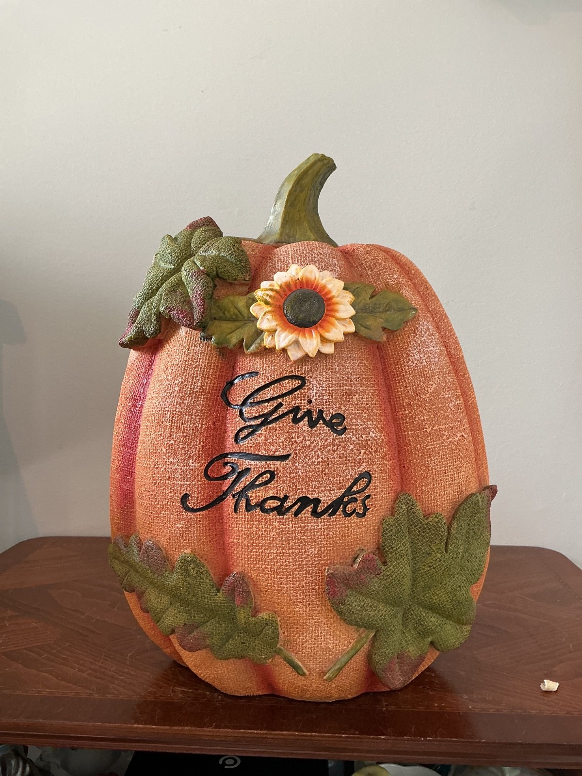 decorative orange resin autumn pumpkin featuring a green stem, a sunflower accen