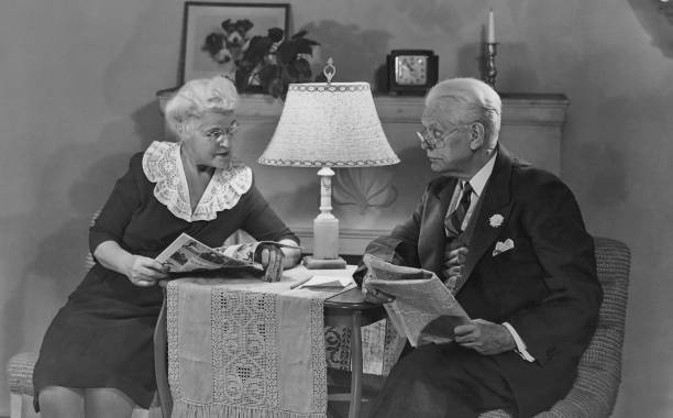 An old man reads a newspaper as wife looks through a magazine 1940\'s Old Photo