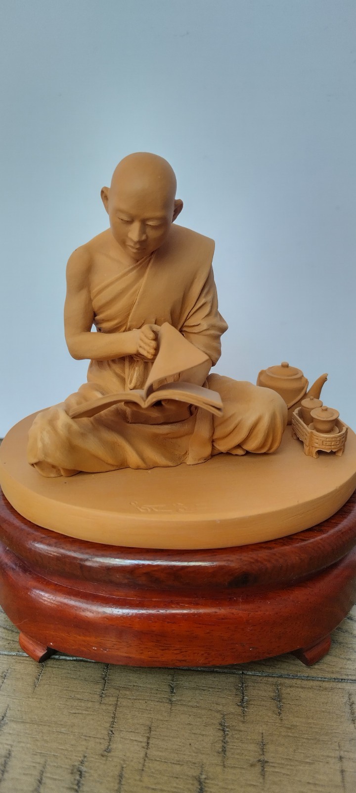 Buddhist Monk Statue reading meditating on a wooden pedestal. Tea set