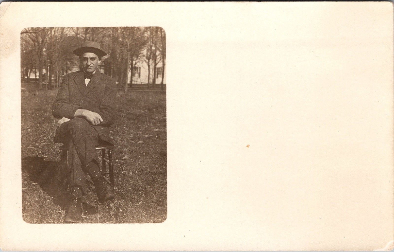 Postcard Real Photo RPPC Man Wearing Hat & Tie Sitting on Chair in Field