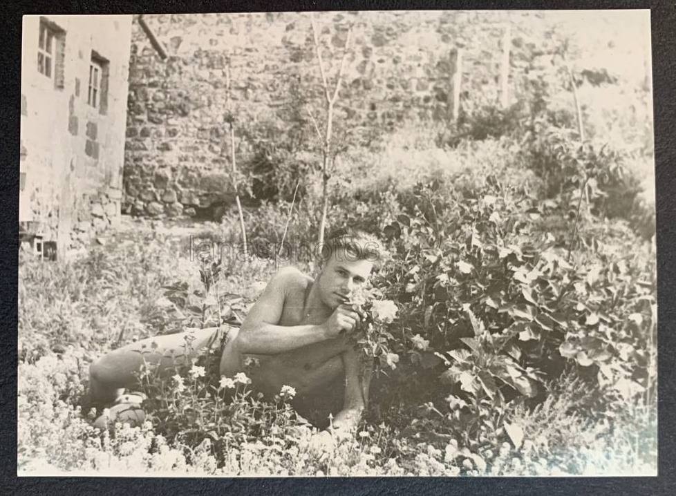 Romantic mood Flowers Handsome lone man lying in grass Bare torso photo Gay Int